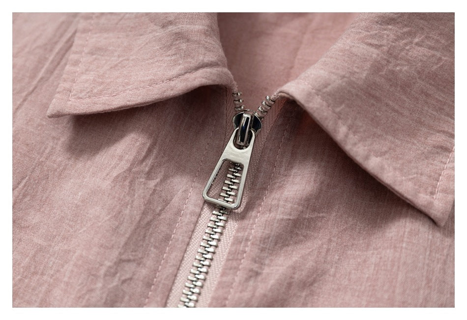Close-up of the metal zipper pull and teeth between the pointed collar on a dusty rose shirt-jacket.