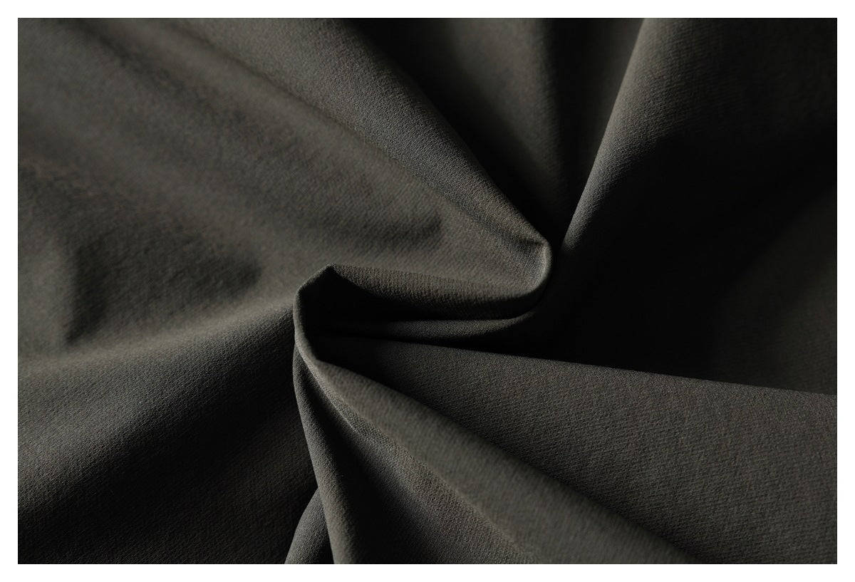Close-up of dark charcoal fabric gathered into folds, showing its surface and drape.
