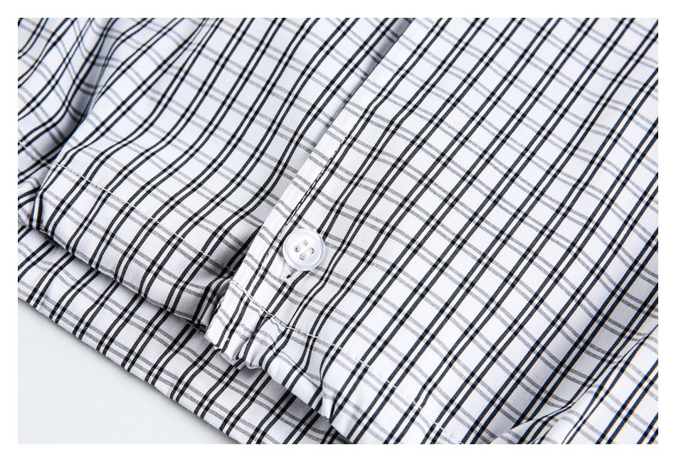 Close-up of a white button on white fabric with a black and gray plaid pattern.