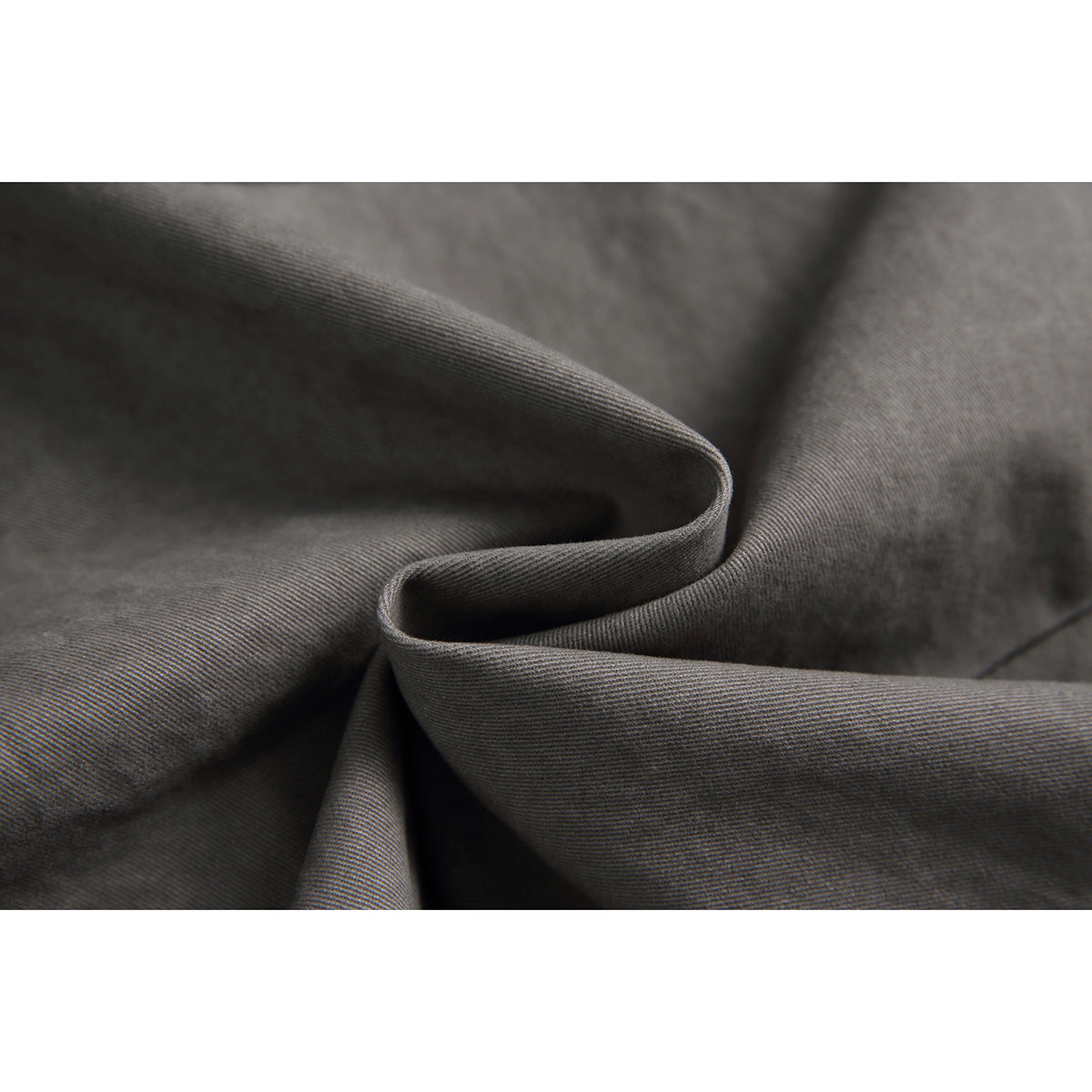 Close-up of gray fabric draped to show its fine diagonal weave and texture.