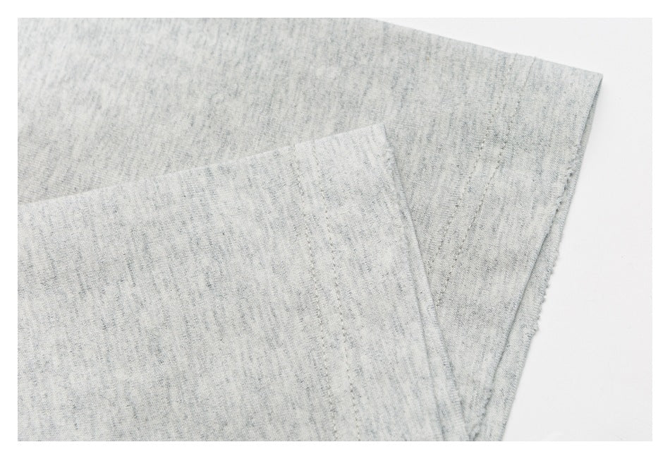 Close-up of overlapping fabric and stitched seams on the light gray heather T-shirt.