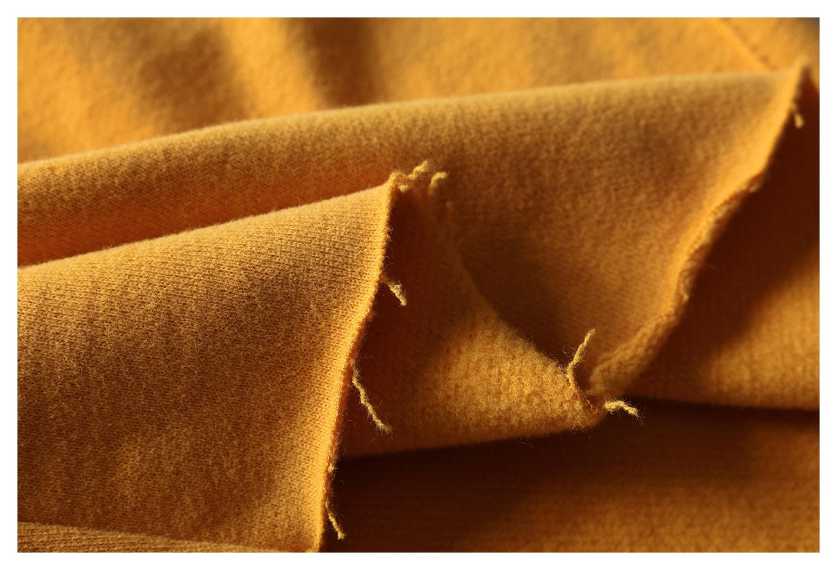 Close-up of folded mustard fabric showing its textured surface and unfinished, frayed edges.