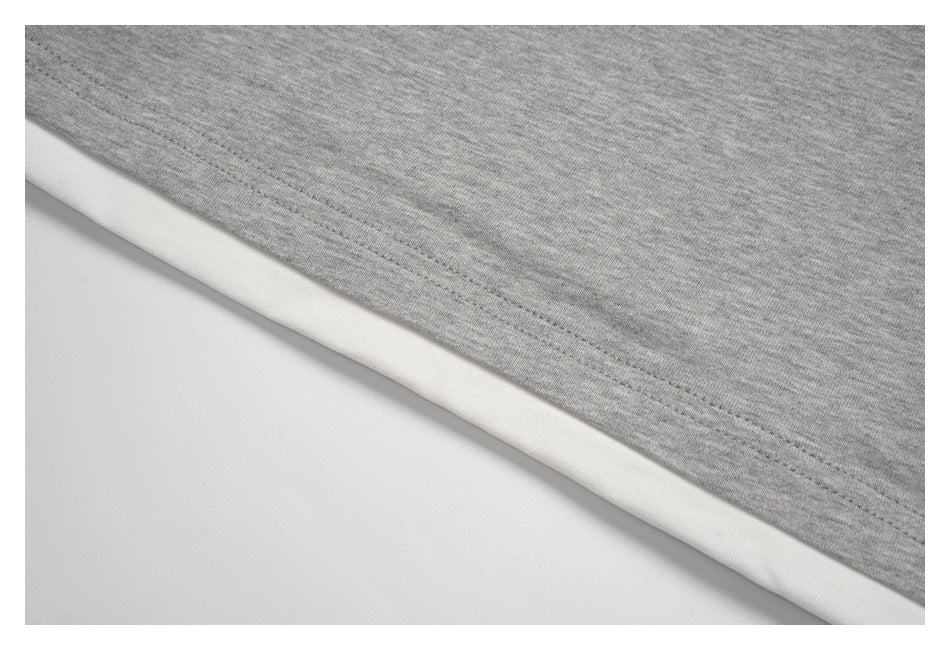 Close-up of a heather-gray garment hem with a white layer visible beneath.