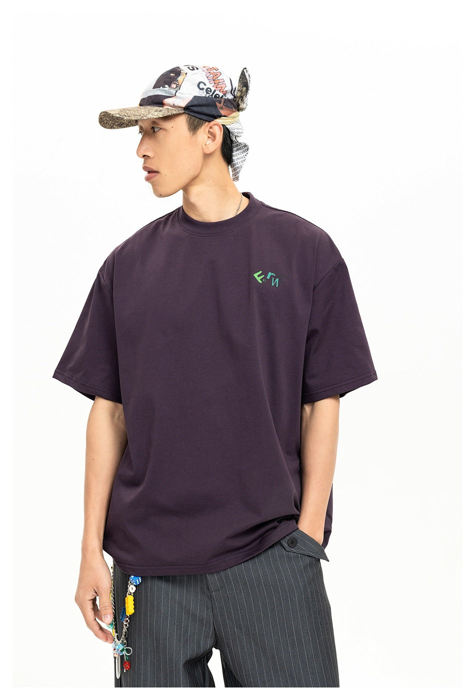 Model wearing a dark plum oversized T-shirt with a small green and teal chest logo.
