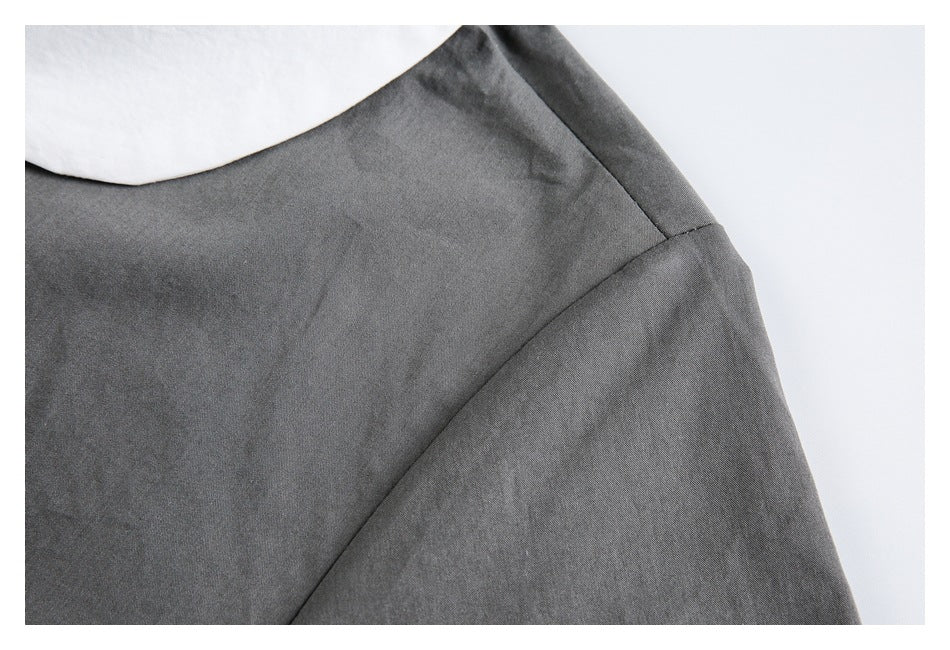 Close-up of the charcoal gray shirt shoulder seam and sleeve beneath the edge of its white collar.