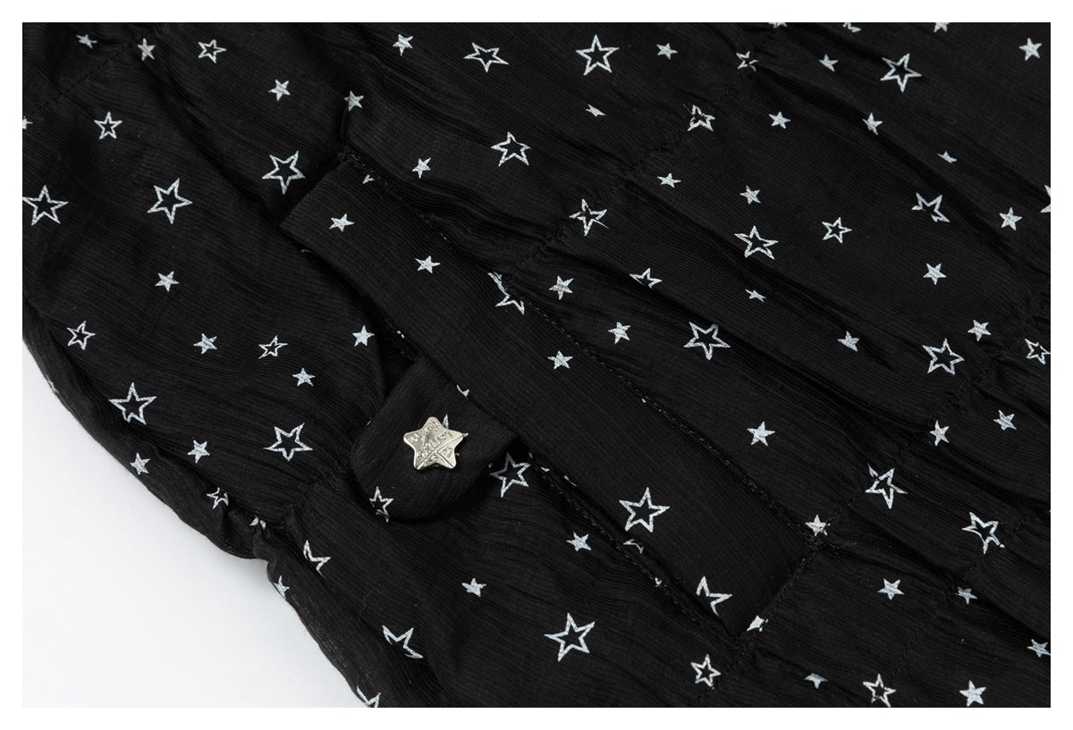 Close-up of black star-print garment fabric with a small silver star-shaped button on a tab.