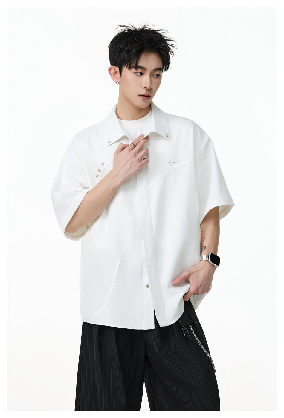 Closer view of a model wearing an oversized white short-sleeve shirt with a pointed collar and decorative details.