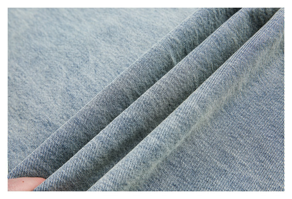 Close-up of light blue denim folded into soft ridges, showing its diagonal weave.