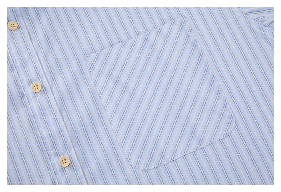 Close-up of the chest pocket and button placket on a light blue shirt with fine vertical stripes.