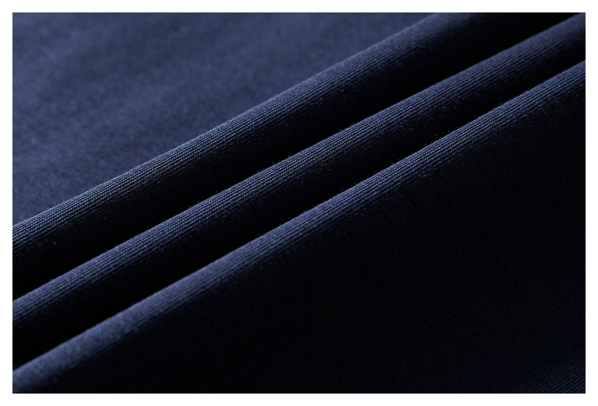 Macro view of dark navy garment fabric draped into folds, showing its surface texture.