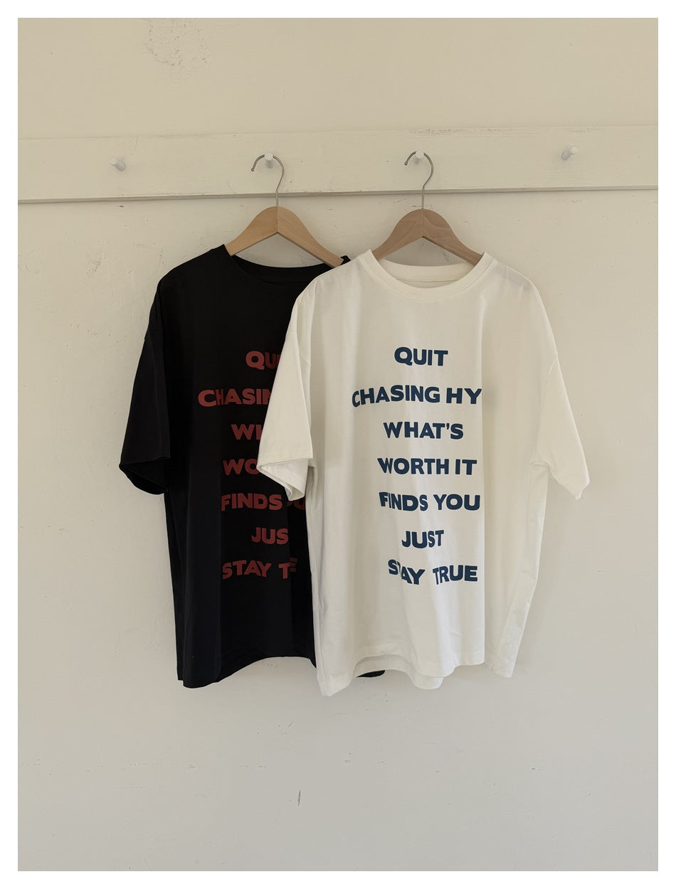 Black and white graphic T-shirts hanging side by side; the white shirt has a navy text print.