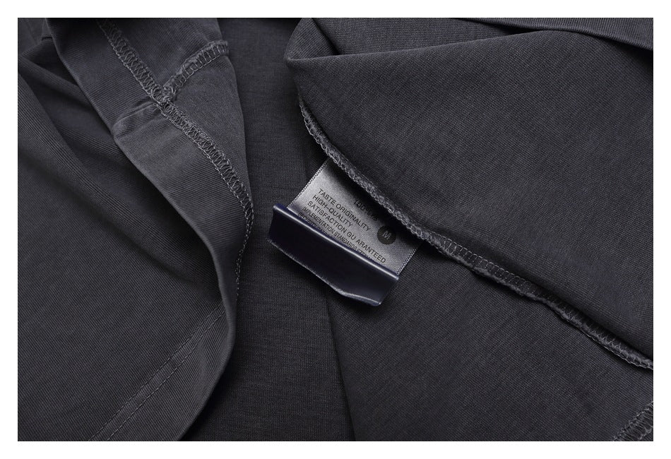 Inside view of the charcoal T-shirt showing overlock seams and a sewn-in English text label.