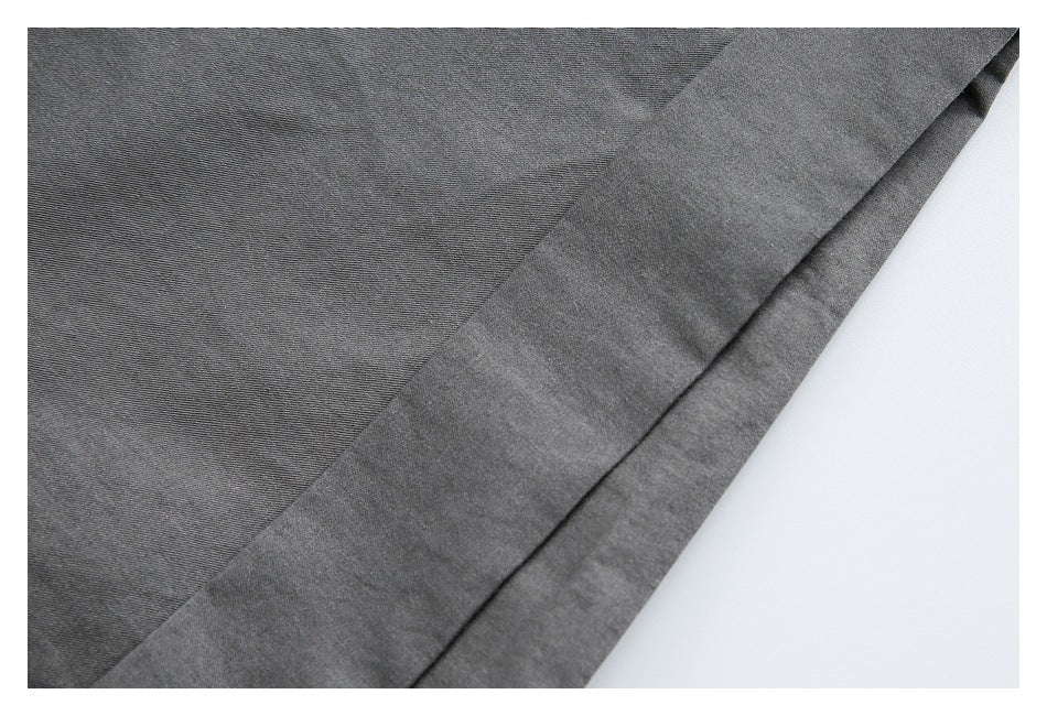Close-up of charcoal gray garment fabric with fine texture and a folded edge.