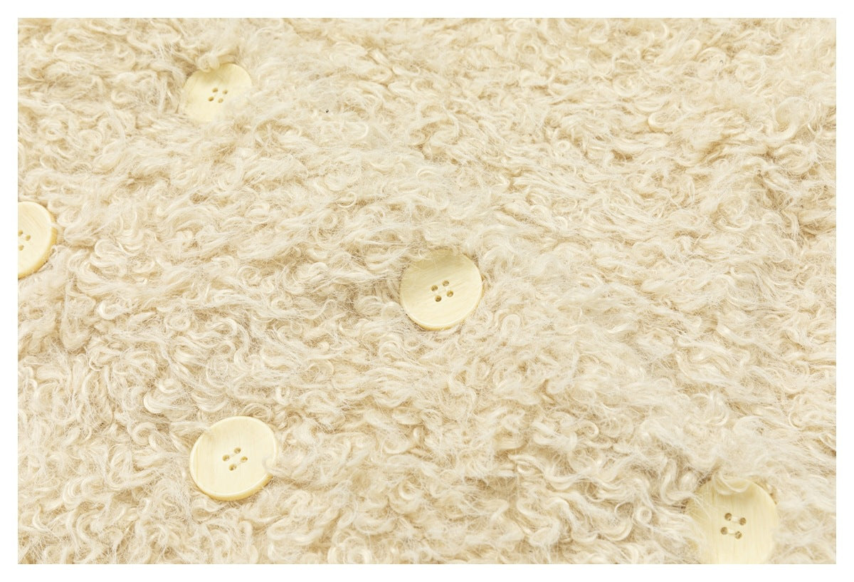 Close-up of the cream jacket’s curly surface texture and pale buttons.
