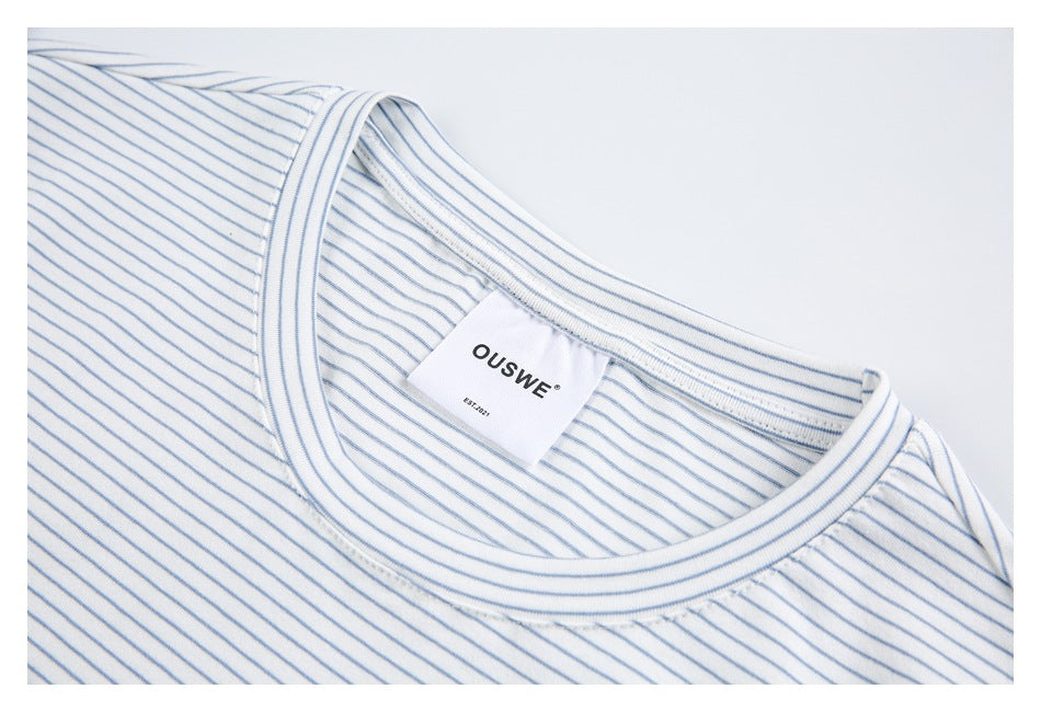 Close-up of a white shirt with thin blue stripes, showing the ribbed crew neckline and sewn-in neck label.