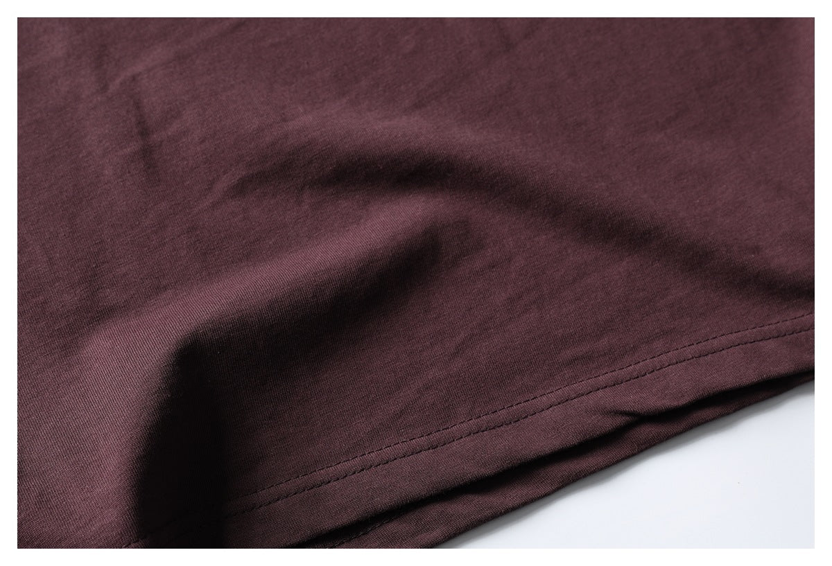 Close-up of the stitched bottom hem of a burgundy T-shirt.