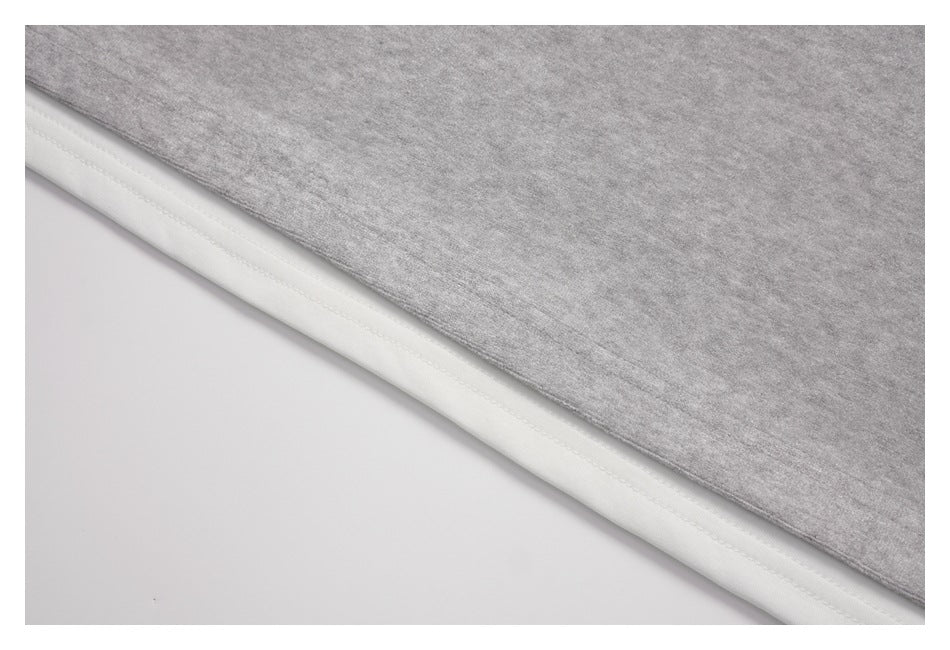 Close-up of a light gray top's bottom edge layered over a white inner hem.