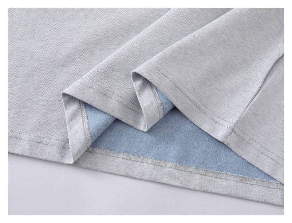 Close-up of a light gray garment hem with pale blue inner fabric and stitched seams.