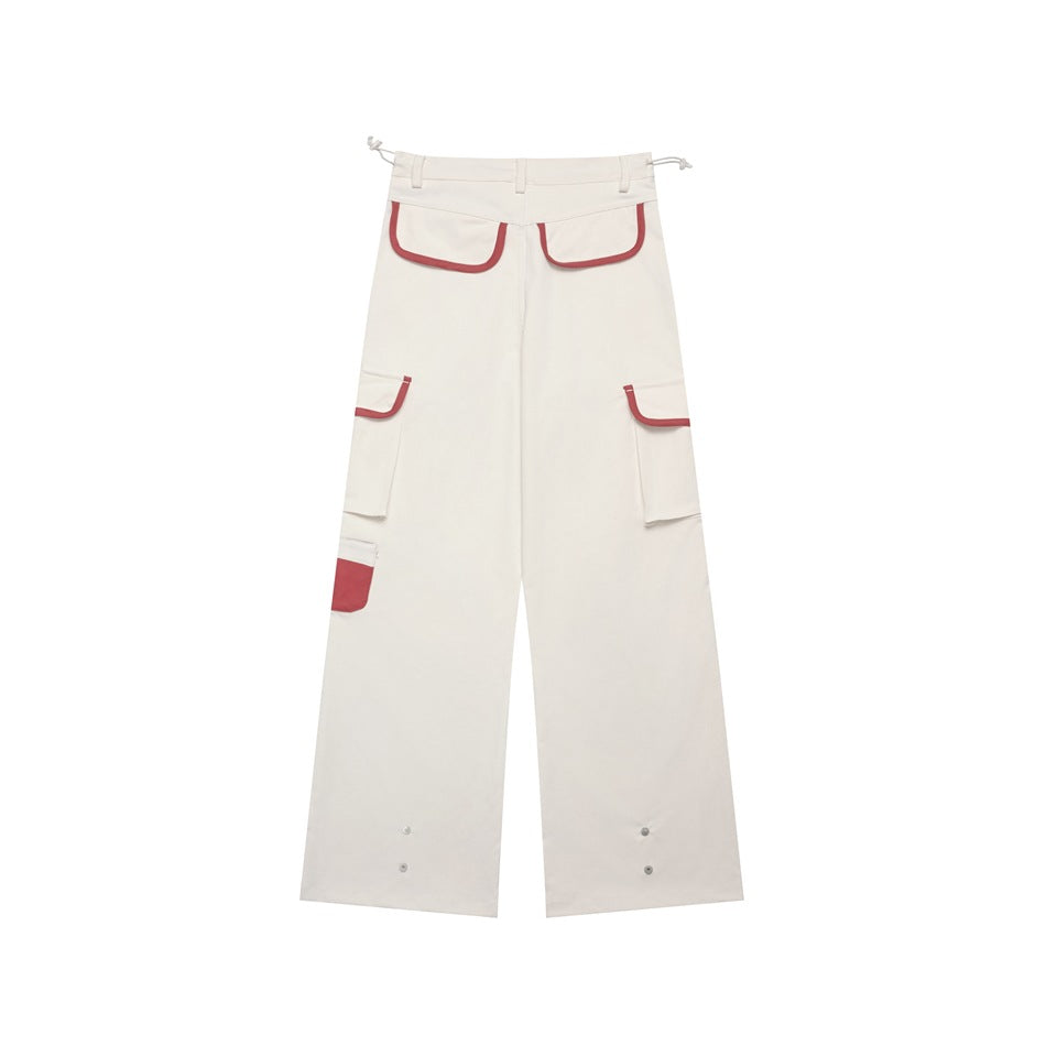 Full view of ivory wide-leg cargo pants with burgundy-trimmed pockets and adjustable ankle snaps.