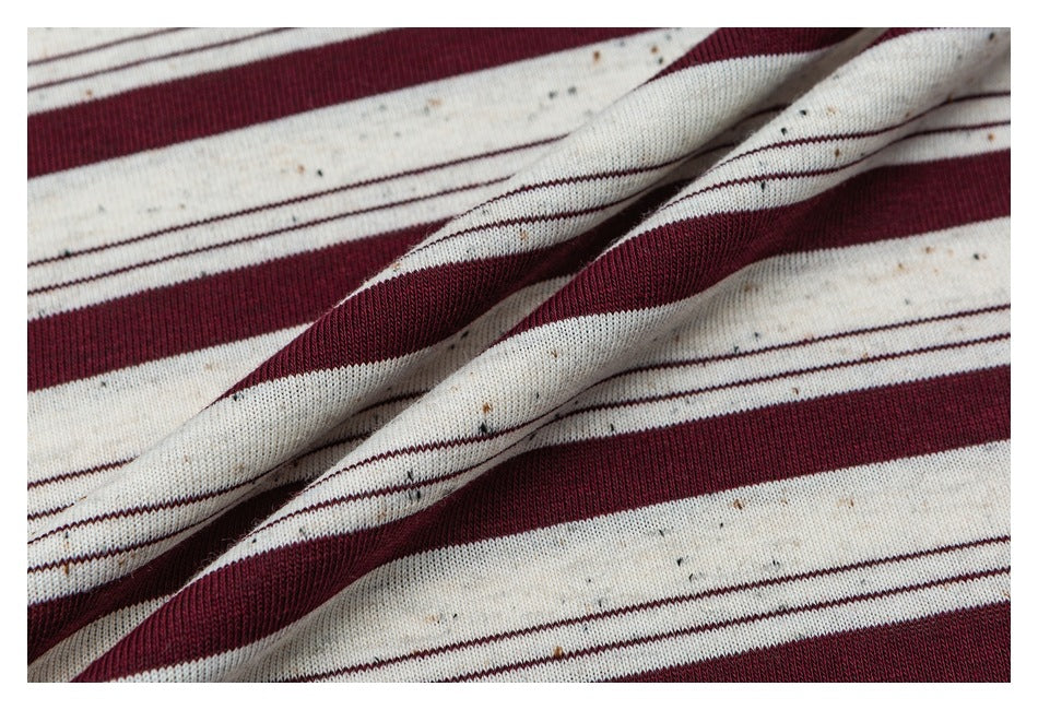 Close-up of cream and burgundy striped fabric draped to show its texture and folds.