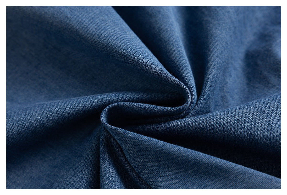 Close-up of dark blue denim fabric arranged in soft folds, showing its textured surface.