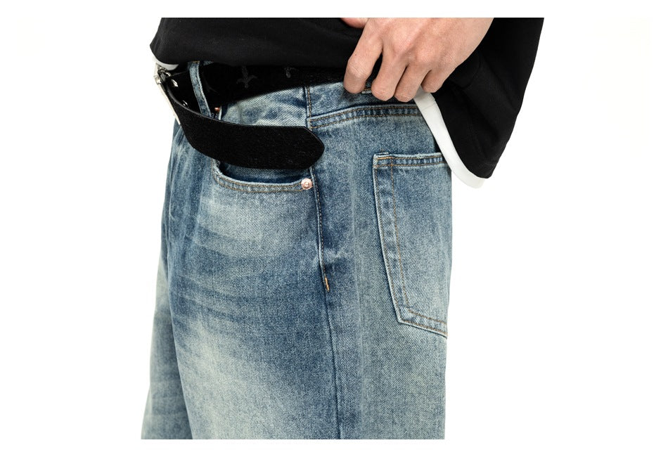 Close-up of the light blue jeans’ front waist, pocket, belt loops and button, with the waistband opened by hand.