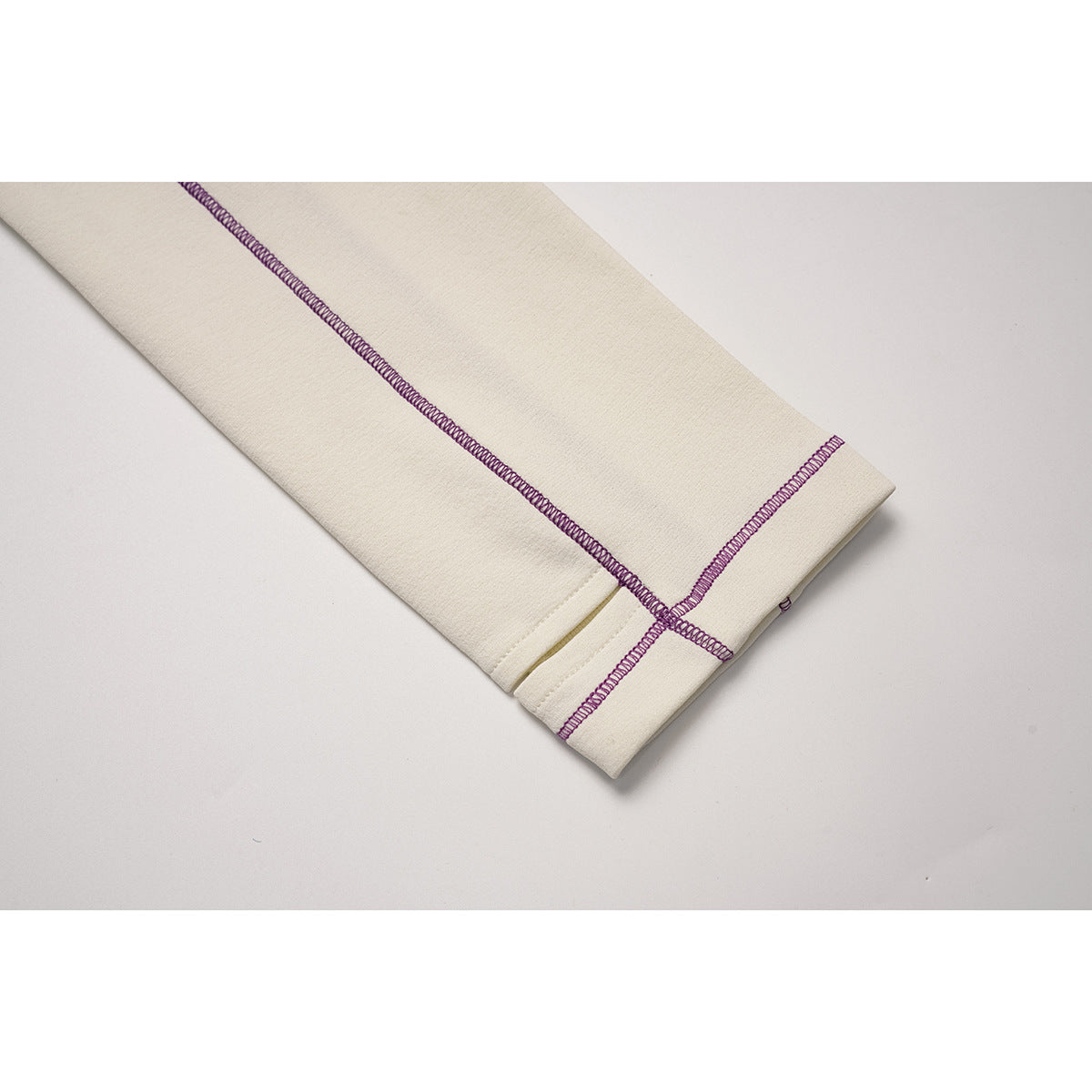 Close-up of an ivory sleeve cuff with purple overlock seam detailing.