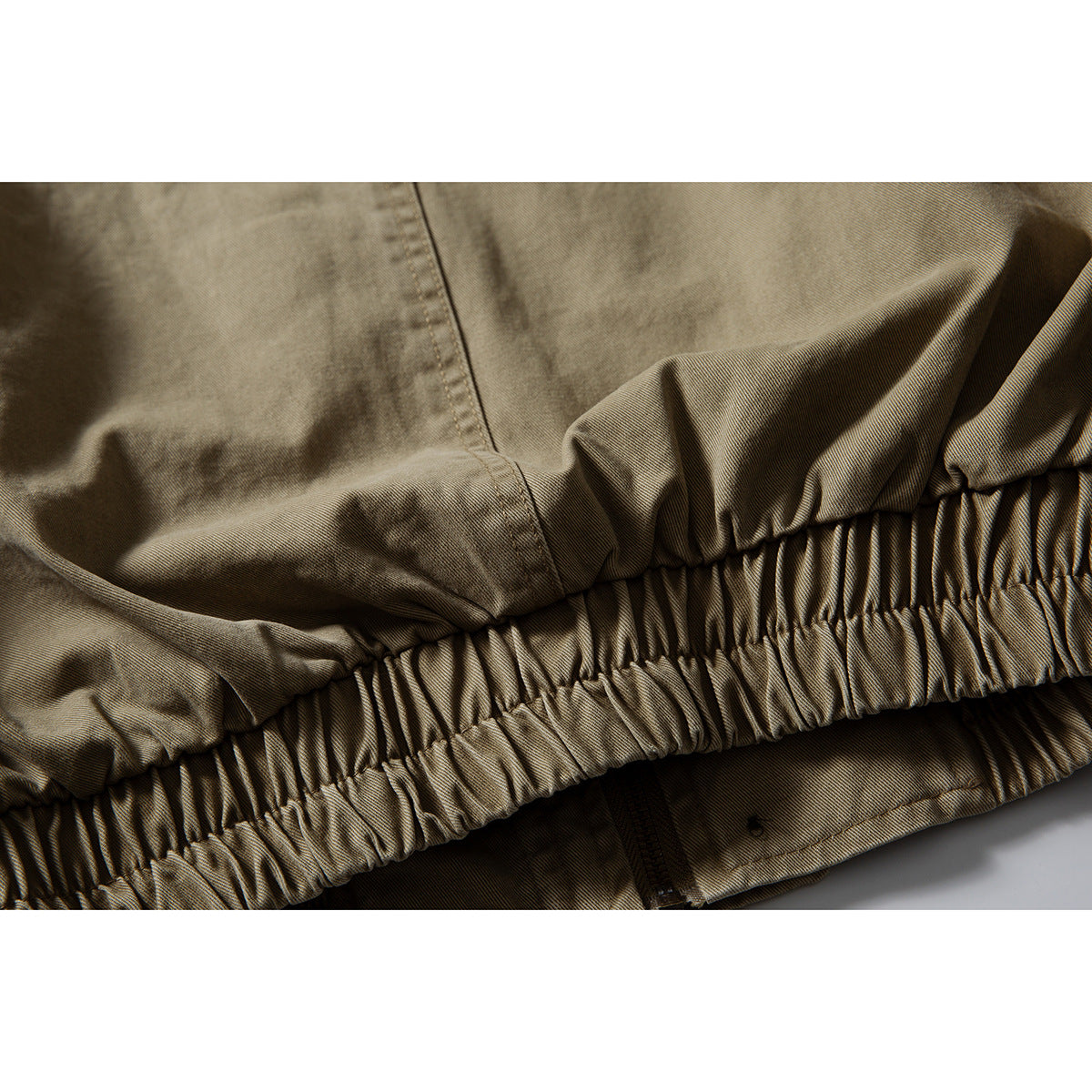 Close-up of the jacket's gathered elastic waist hem and a partially visible zipper.