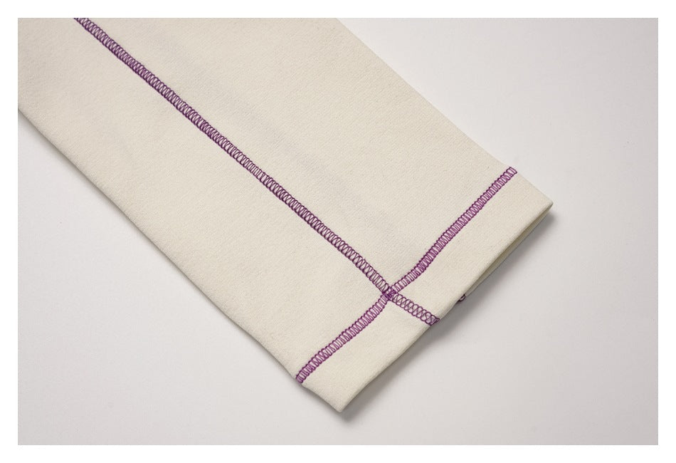 Close-up of an ivory garment cuff or hem with purple overlock stitching.