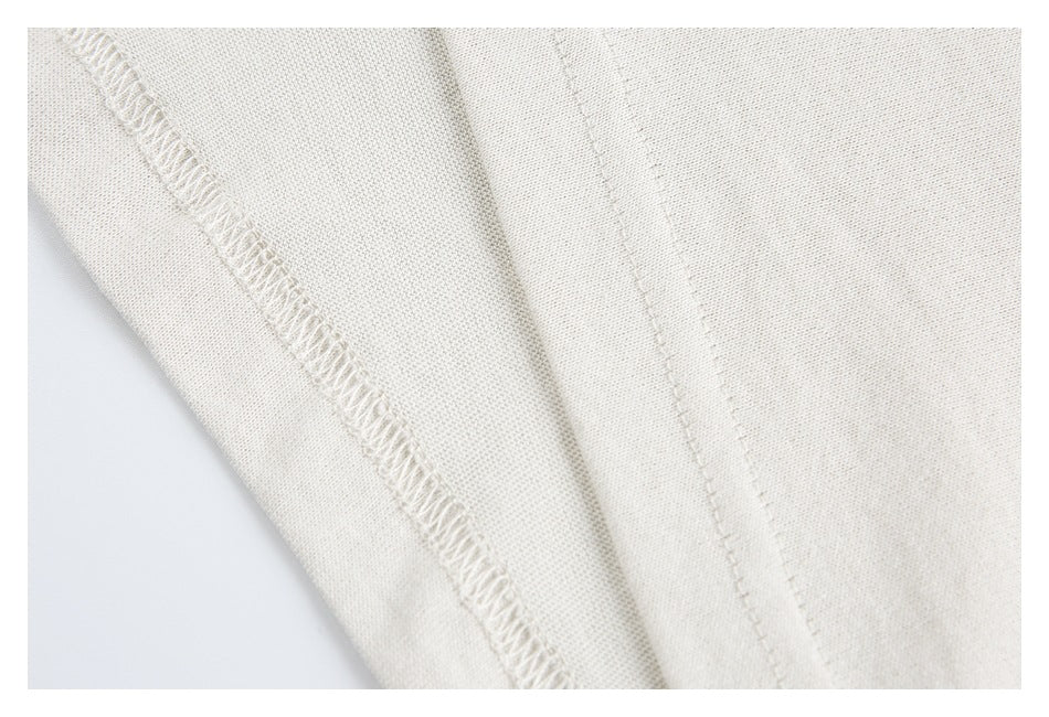 Close-up of off-white garment fabric showing overlocked stitching and a seam.