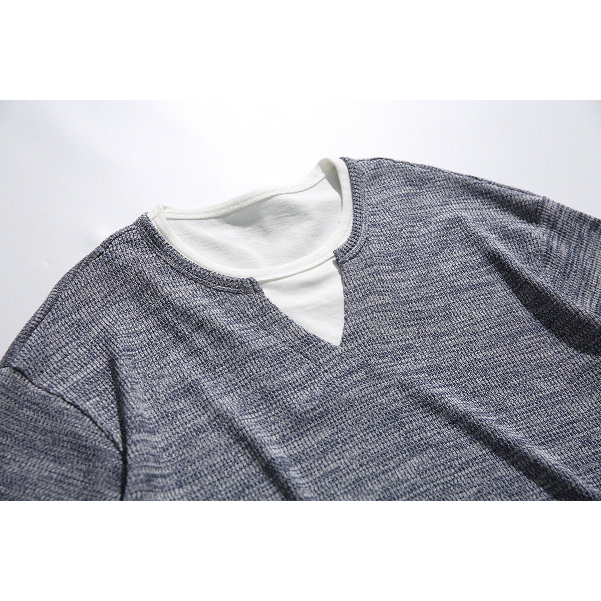 Close-up of a blue-gray textured short-sleeve shirt's white-trimmed neckline and V-shaped inset.