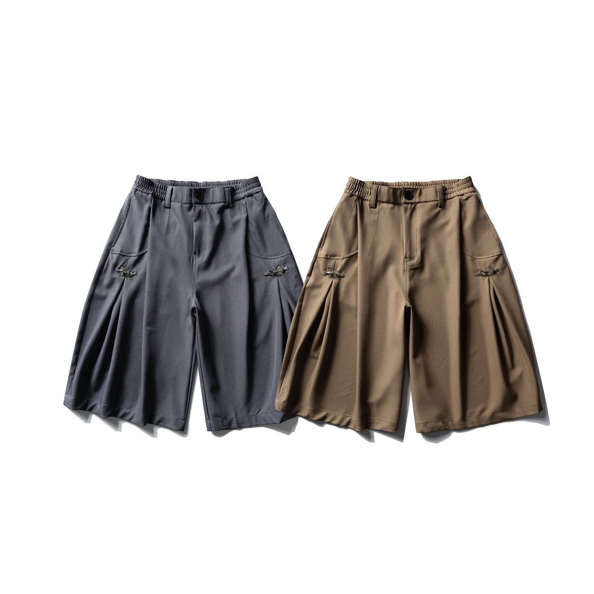 Front view of wide-leg shorts in charcoal gray and brown, with elastic waistbands, slanted pockets and side clasps.
