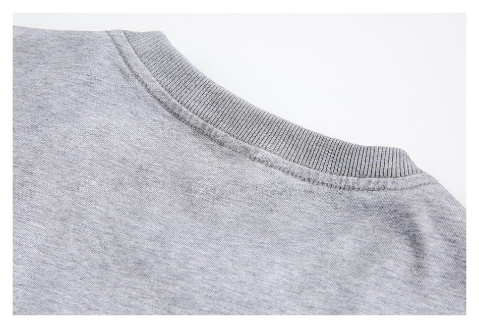 Close-up of the ribbed crew neckline and shoulder seam on a light heather gray top.