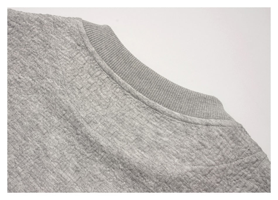 Close-up of a light gray garment showing a ribbed neckline and textured stitching.