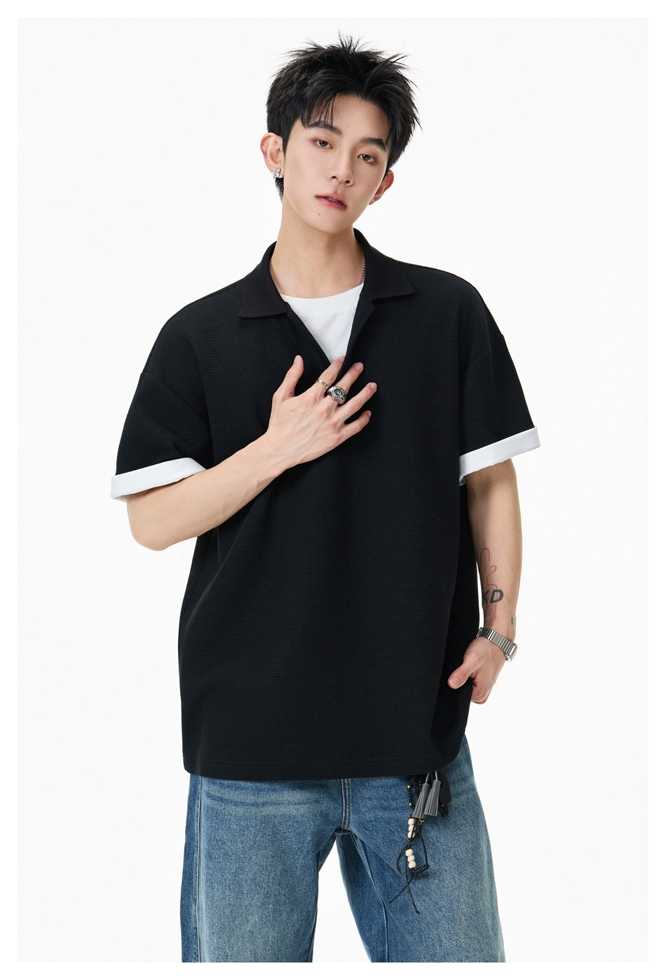 Model wearing black waffle-textured polo-style top with white layered neckline and cuffs, close-up of upper body