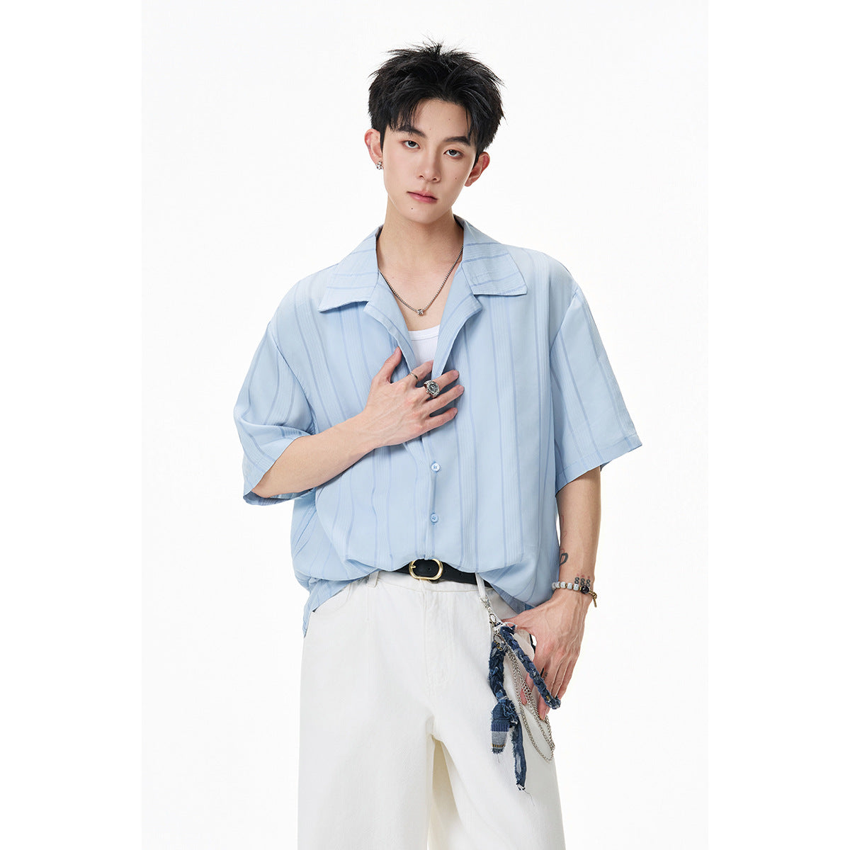 Model wearing a loose light-blue short-sleeve shirt with vertical stripes and white trousers.