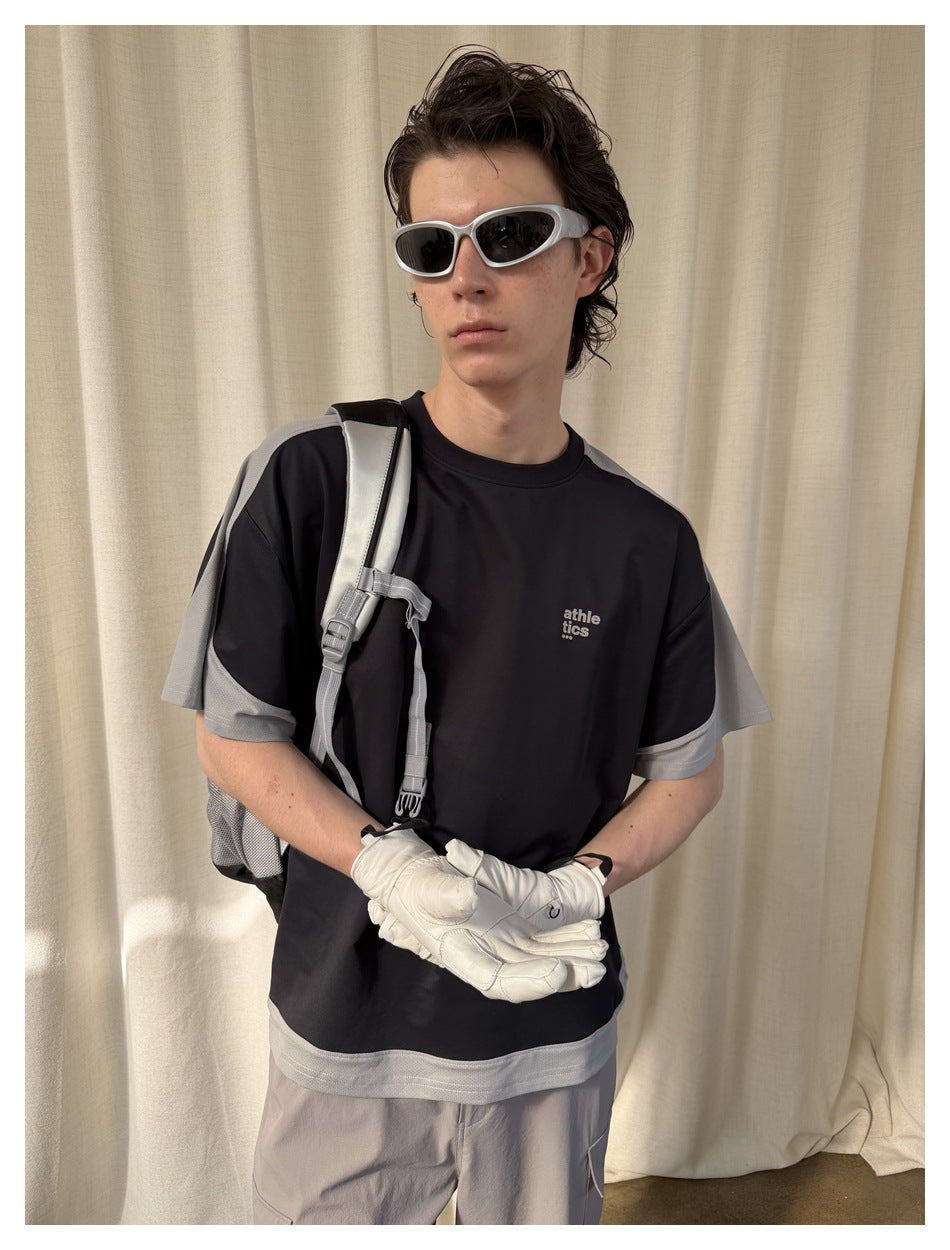 Close view of a model wearing a black T-shirt with gray sleeves and hem; small text is printed on the chest.