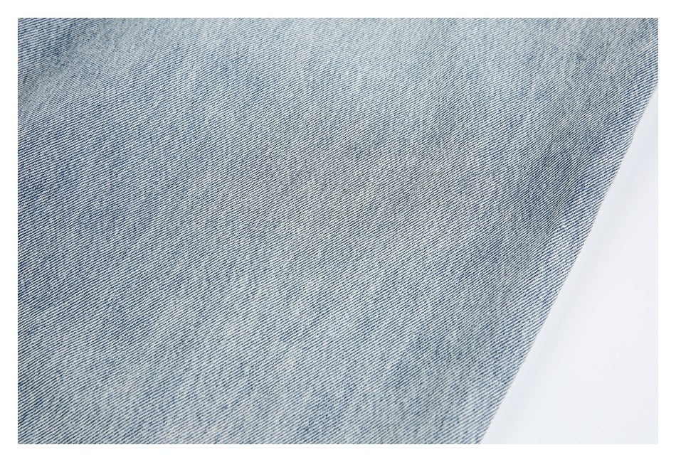 Close-up of the light blue denim surface showing its diagonal weave and subtle variation in color.