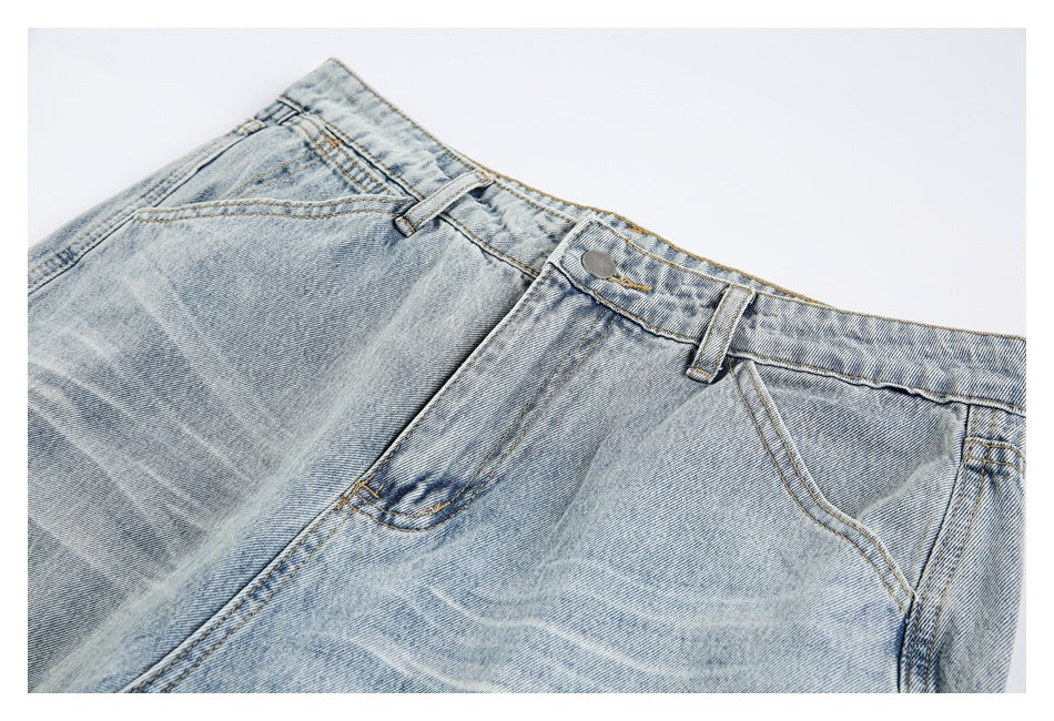 Close-up of the front waistband, button, belt loops, and pockets on faded light-blue jeans.
