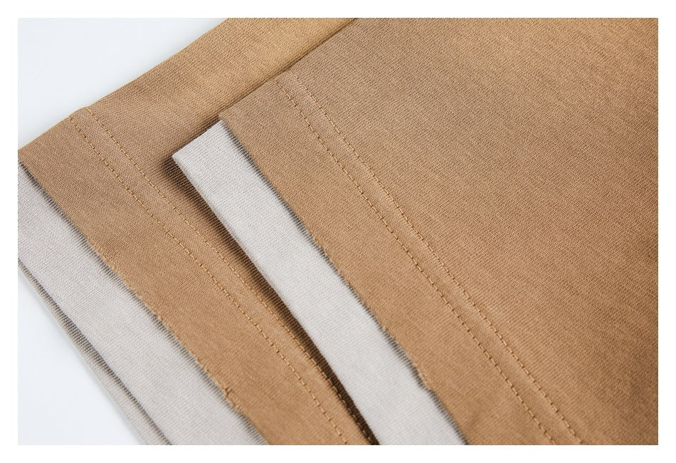 Close-up of tan garment edges with stitched seams and pale gray reverse fabric visible between layers.