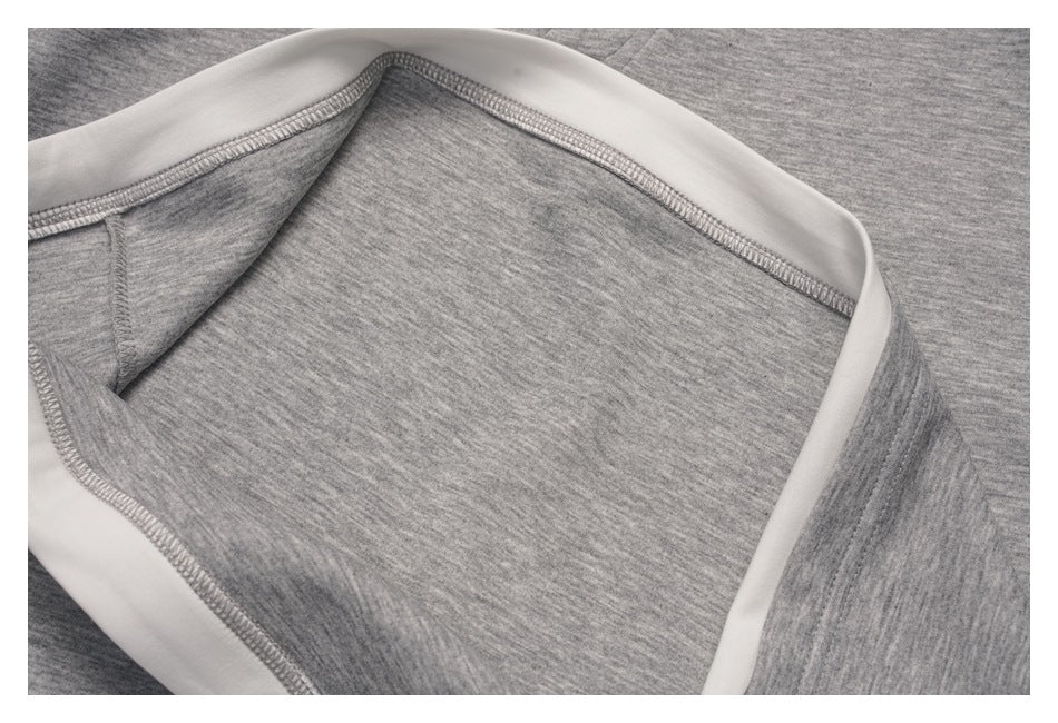 Close-up of gray knit garment interior with white binding and visible overlock stitching.
