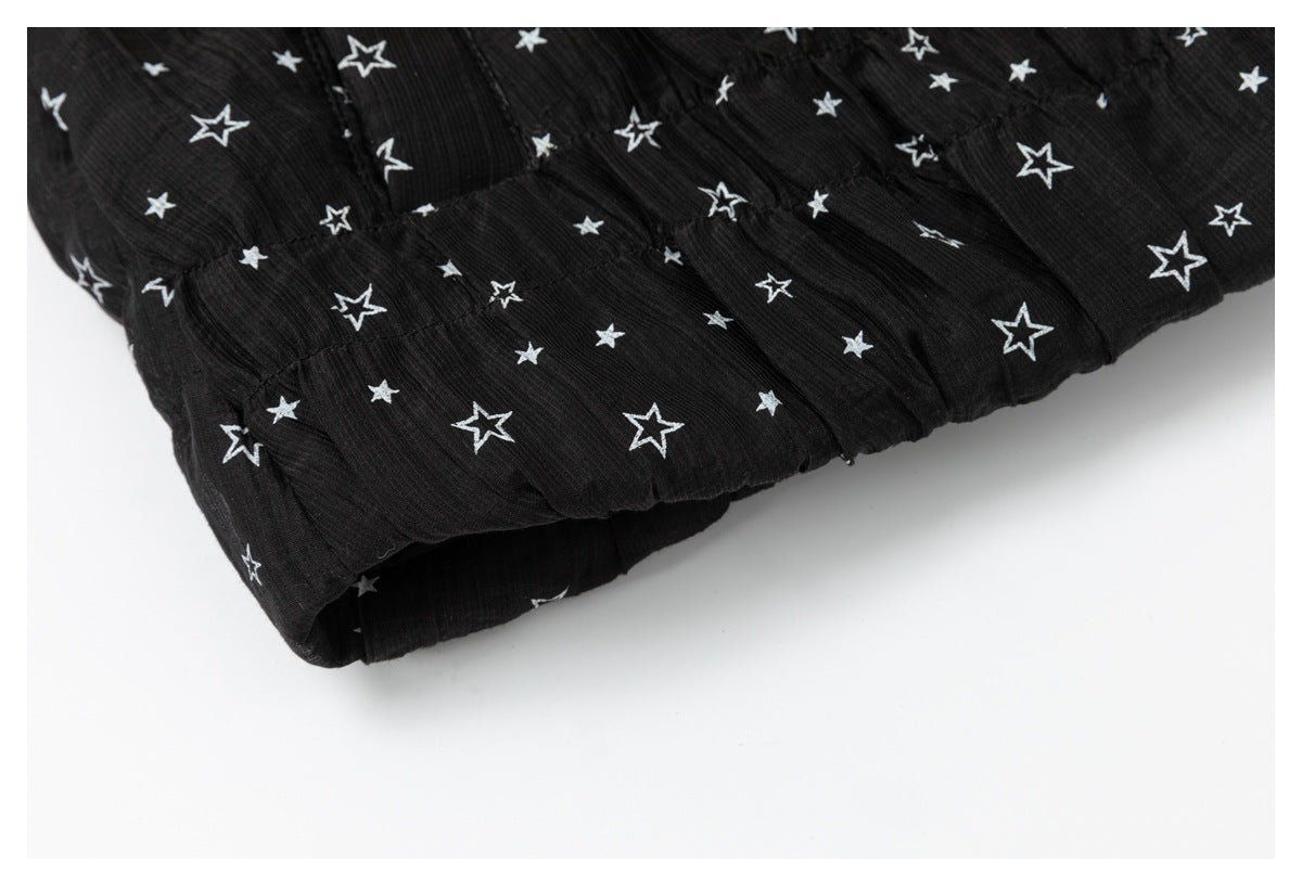 Close-up of the gathered, folded edge of a black garment with a white star print.