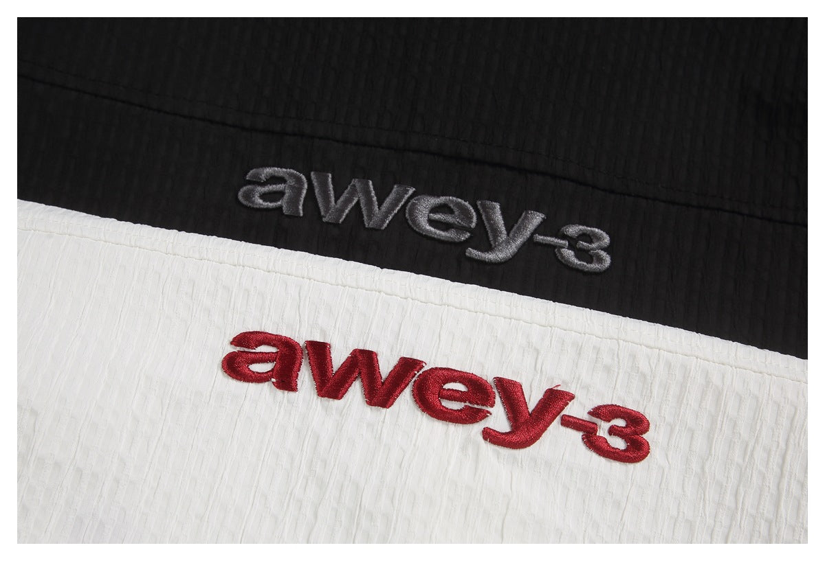 Close-up of gray and red embroidered lettering on black and white textured fabric.