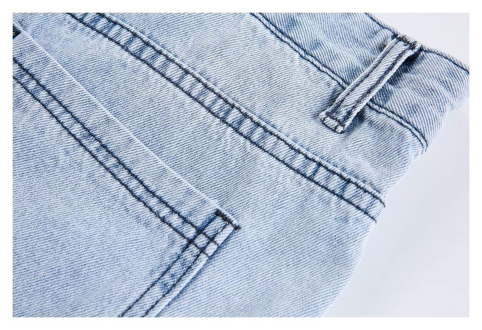 Close-up of light-wash jeans showing back pocket stitching, waistband seam, and belt loop.