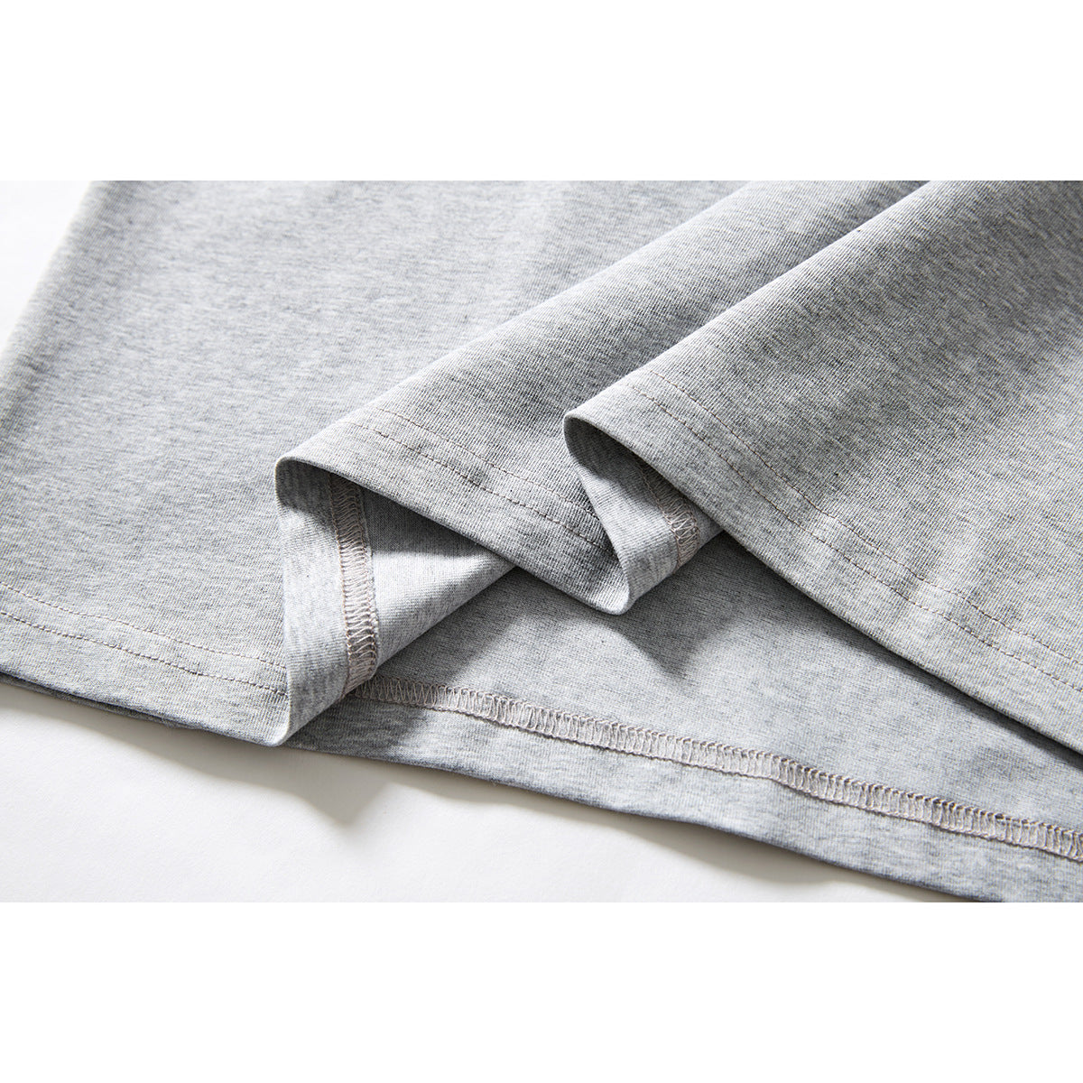 Close-up of a light gray T-shirt’s folded sleeve and stitched hem.