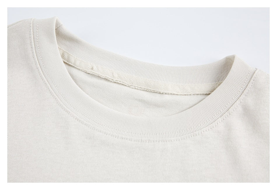 Close-up of the ribbed crew neckline and inner seam of an off-white shirt.