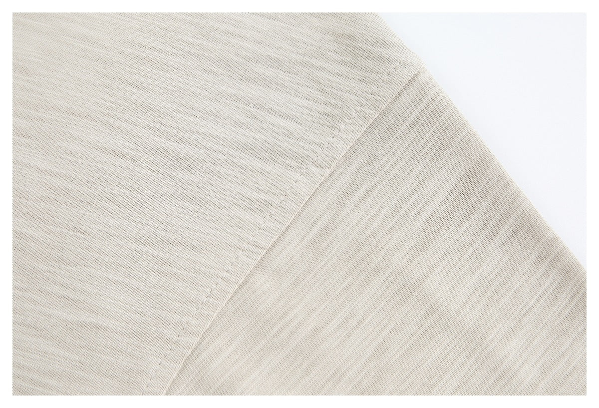 Close-up of a shoulder seam on beige heathered garment fabric.
