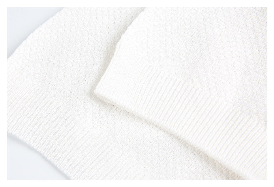 Close-up of the white knit polo shirt's ribbed sleeve cuff against its textured body.