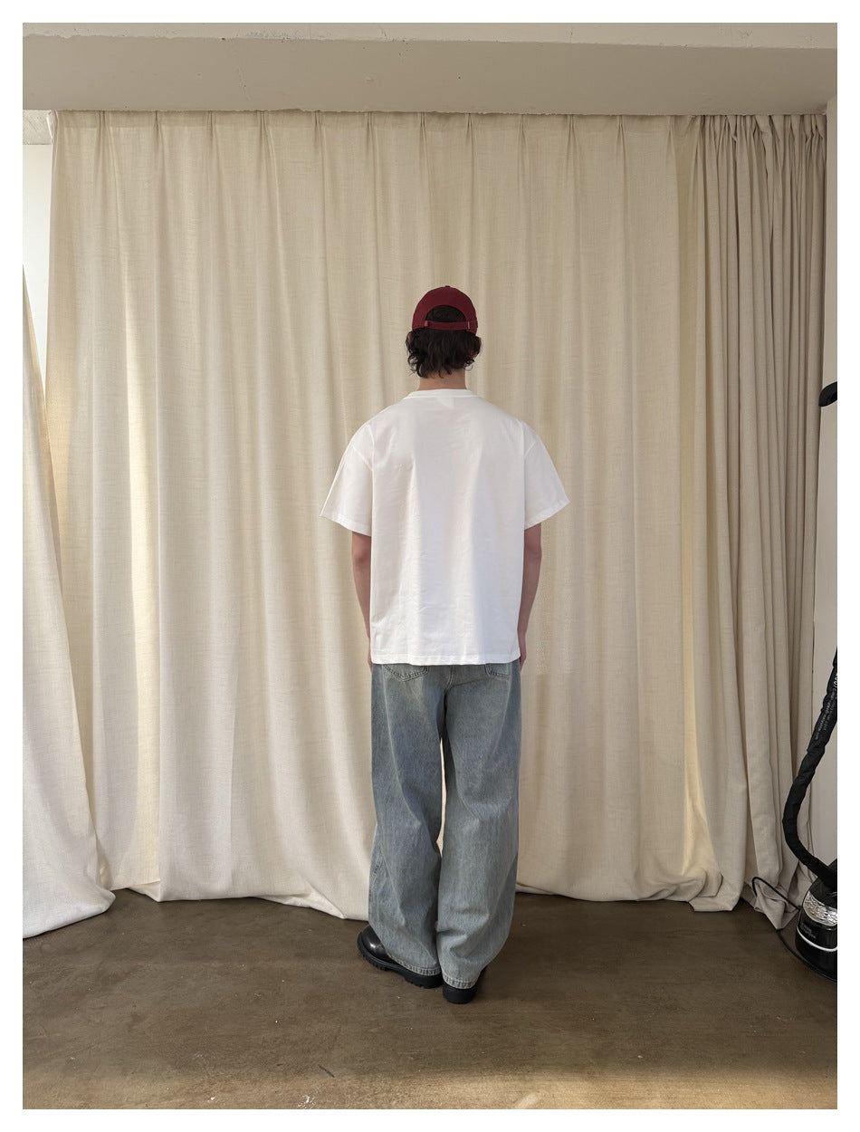 Back view of a model wearing a plain white T-shirt and loose light-wash jeans.