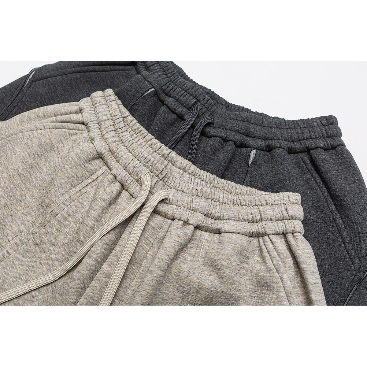 Close-up of light gray and charcoal shorts showing elastic waistbands, drawstrings, and front pockets.